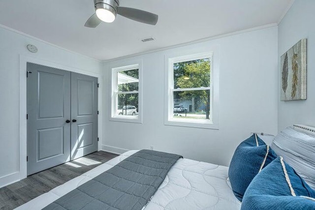 bedroom featuring a closet, crown molding, ceiling fan, and dark wood-type flooring