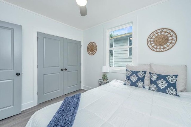 bedroom with a closet, ceiling fan, hardwood / wood-style floors, and ornamental molding