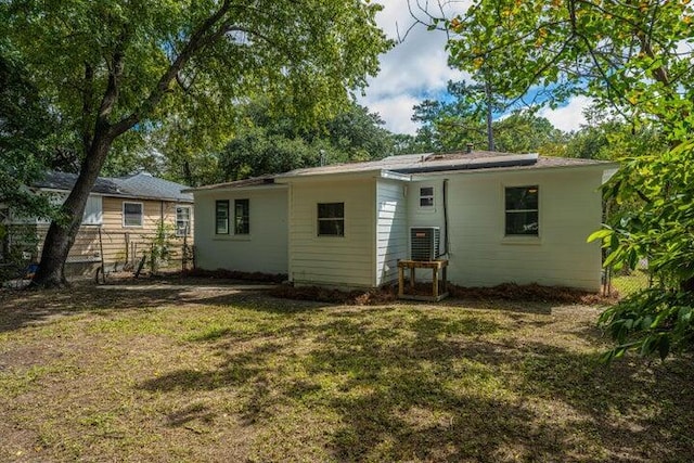 rear view of property with central air condition unit and a yard