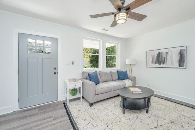 living room with light hardwood / wood-style floors, ceiling fan, and ornamental molding