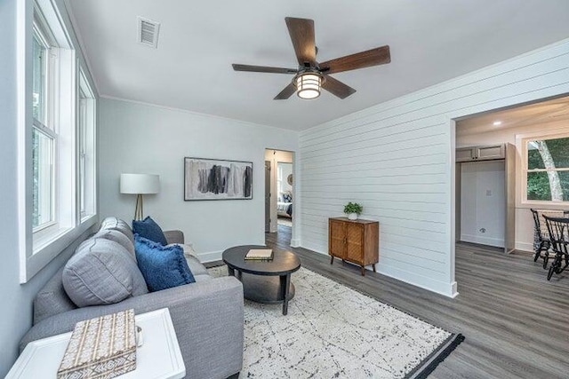 living room featuring plenty of natural light, ceiling fan, and dark hardwood / wood-style flooring