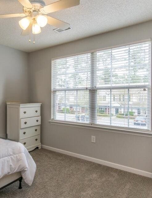 bedroom featuring light carpet, a textured ceiling, and ceiling fan