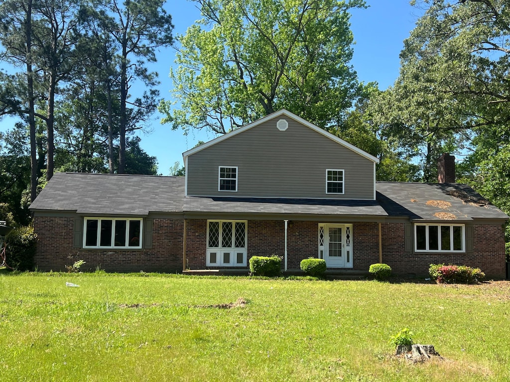 view of front of home with brick siding, a chimney, and a front yard