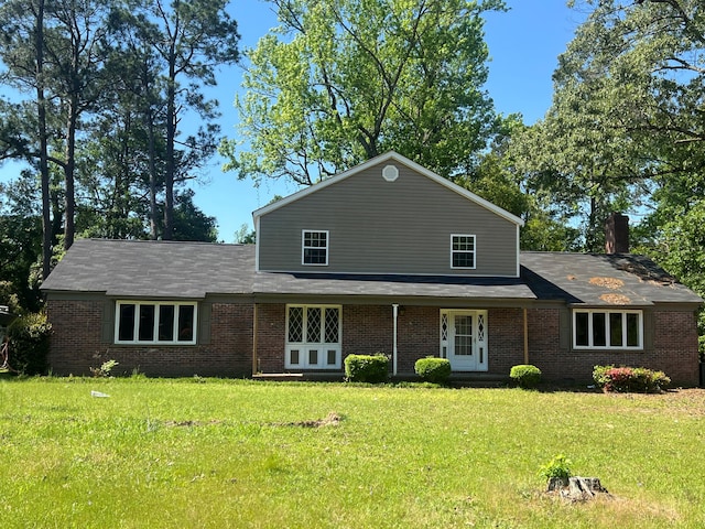 view of front of home with brick siding, a chimney, and a front yard