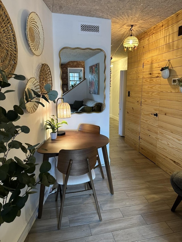 dining room featuring wooden walls, wood finished floors, and visible vents