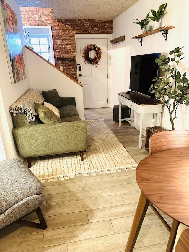 living area with wood finished floors and brick wall