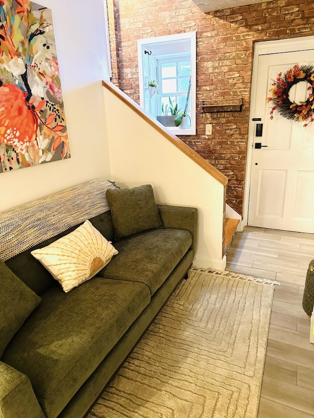 living room featuring stairway, wood finished floors, and brick wall