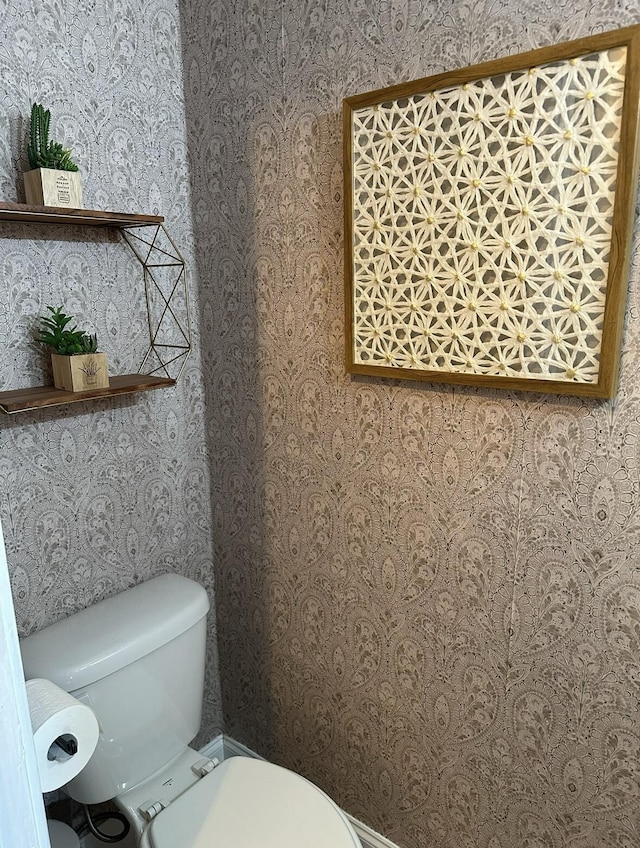 half bath featuring toilet and wallpapered walls