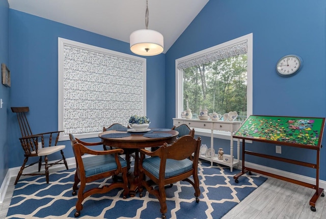 dining area with baseboards, wood finished floors, and vaulted ceiling