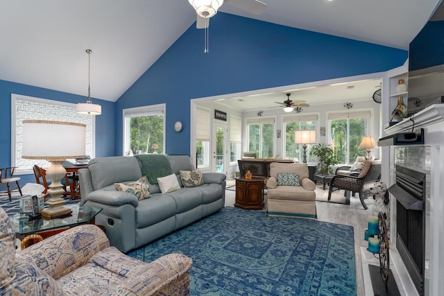 living room featuring a ceiling fan, high vaulted ceiling, a healthy amount of sunlight, and a fireplace
