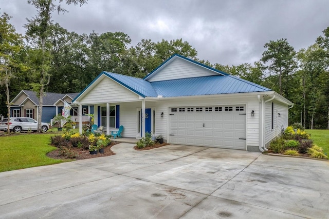 ranch-style house featuring a garage, a front lawn, concrete driveway, metal roof, and a porch