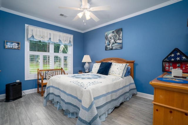 bedroom with crown molding, baseboards, visible vents, and wood finished floors