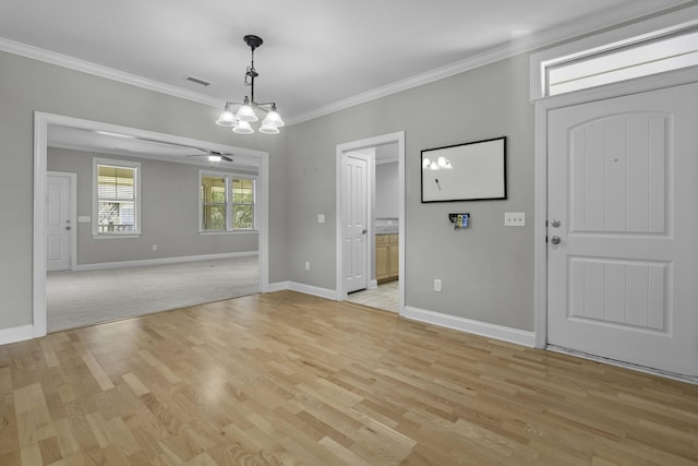 entryway with visible vents, ornamental molding, light wood-type flooring, baseboards, and ceiling fan with notable chandelier