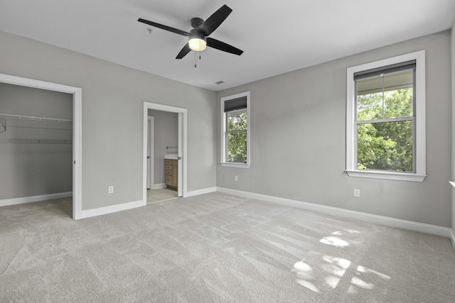 unfurnished bedroom featuring a closet, a spacious closet, connected bathroom, carpet floors, and baseboards
