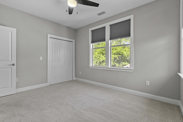 unfurnished bedroom featuring baseboards, visible vents, a closet, ceiling fan, and carpet floors