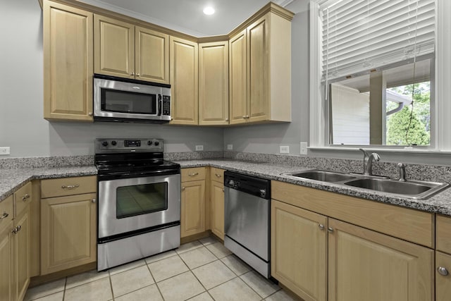 kitchen with light brown cabinets, appliances with stainless steel finishes, a sink, and light tile patterned floors