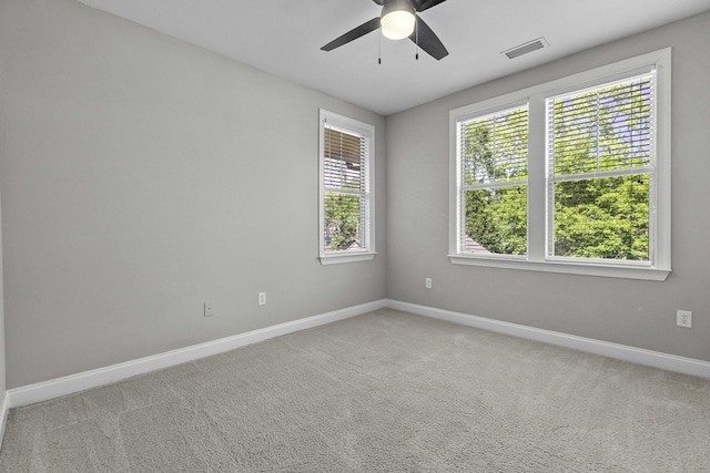 unfurnished room with ceiling fan, light carpet, visible vents, and baseboards