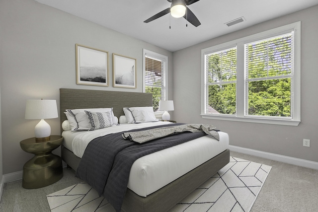 bedroom with baseboards, visible vents, light colored carpet, and ceiling fan