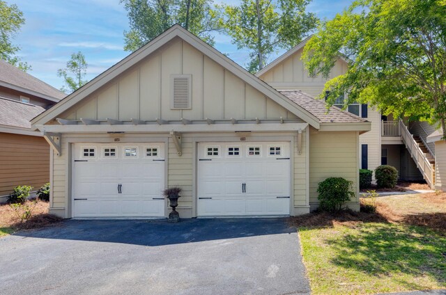 view of front facade featuring board and batten siding, driveway, an outdoor structure, and roof with shingles
