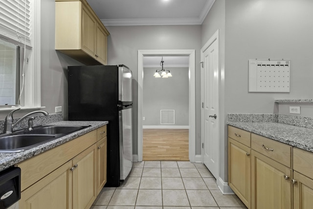 kitchen featuring light brown cabinetry, visible vents, a sink, freestanding refrigerator, and crown molding