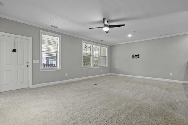 spare room with light colored carpet, ceiling fan, baseboards, and ornamental molding