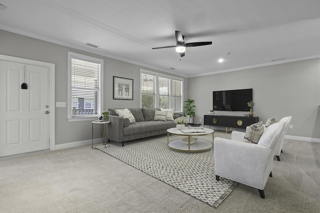 carpeted living area with a healthy amount of sunlight, crown molding, baseboards, and a ceiling fan