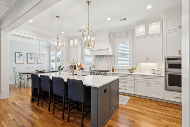 3858 Sawyers Island Dr, Mount Pleasant, SC 29466 - kitchen featuring visible vents, a kitchen island with sink, a kitchen bar, custom range hood, and an inviting chandelier