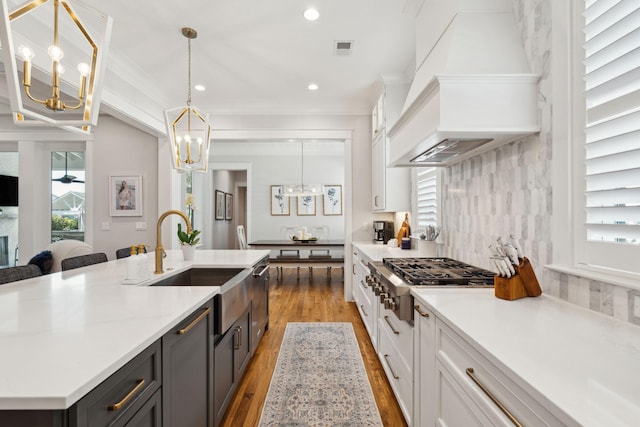 3858 Sawyers Island Dr, Mount Pleasant, SC 29466 - kitchen with a chandelier, a sink, stainless steel gas stovetop, white cabinets, and custom exhaust hood