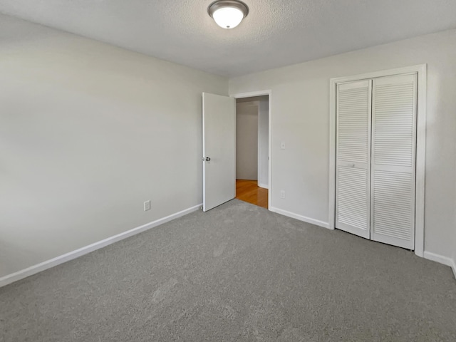 unfurnished bedroom featuring carpet floors, a textured ceiling, and a closet