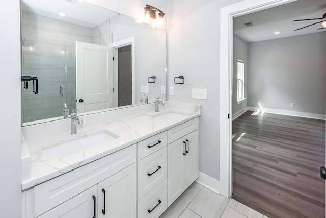 full bath with a sink, double vanity, ceiling fan, and a shower stall