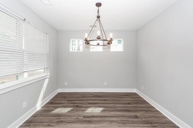 unfurnished room featuring baseboards, an inviting chandelier, and dark wood finished floors