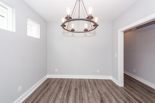 unfurnished dining area with wood finished floors, baseboards, and a chandelier