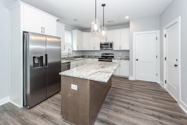 kitchen featuring a kitchen island, dark wood-style flooring, a sink, appliances with stainless steel finishes, and white cabinetry