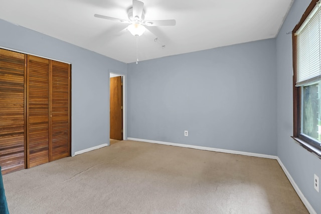 unfurnished bedroom featuring ceiling fan, light colored carpet, and a closet