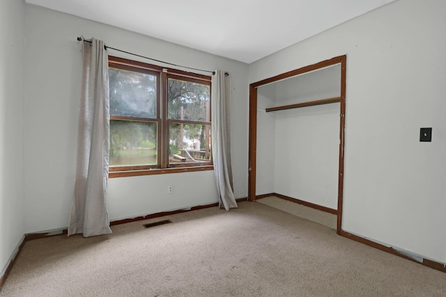 unfurnished bedroom featuring light colored carpet and a closet