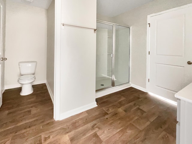 bathroom featuring hardwood / wood-style floors, vanity, a shower with door, and toilet