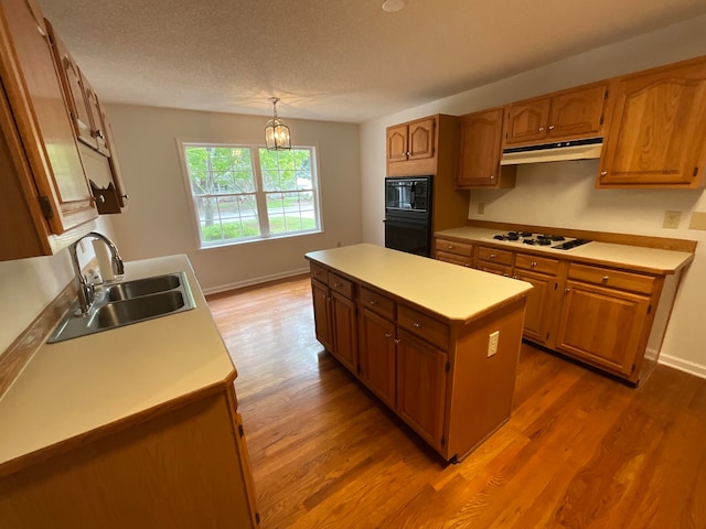 kitchen with sink, white gas stovetop, a center island, hardwood / wood-style floors, and pendant lighting