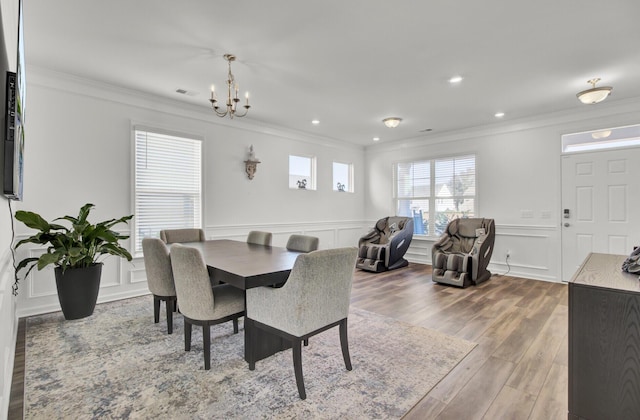 dining space featuring hardwood / wood-style floors, an inviting chandelier, and ornamental molding