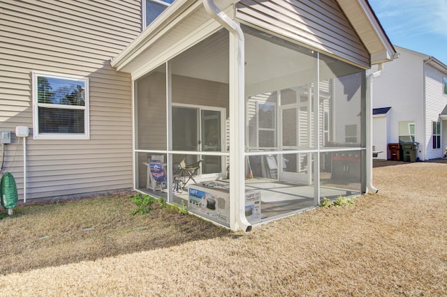 rear view of house featuring a sunroom and a lawn