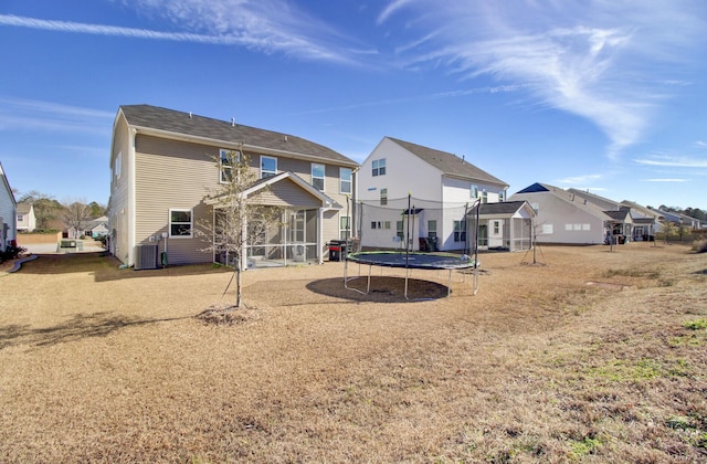 back of house featuring a yard, central AC, and a trampoline