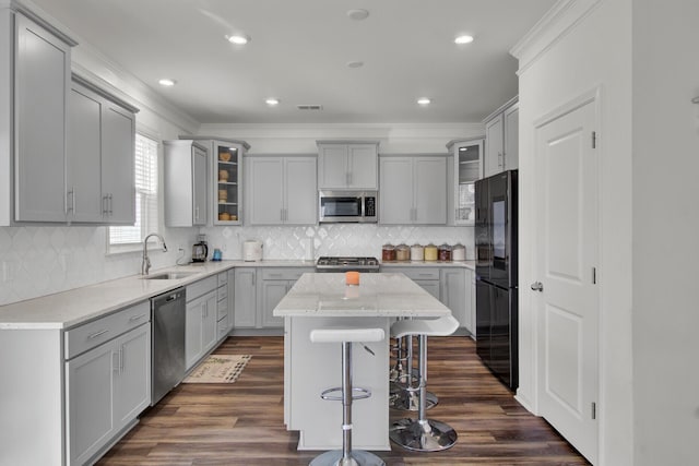 kitchen with appliances with stainless steel finishes, gray cabinetry, a center island, and sink