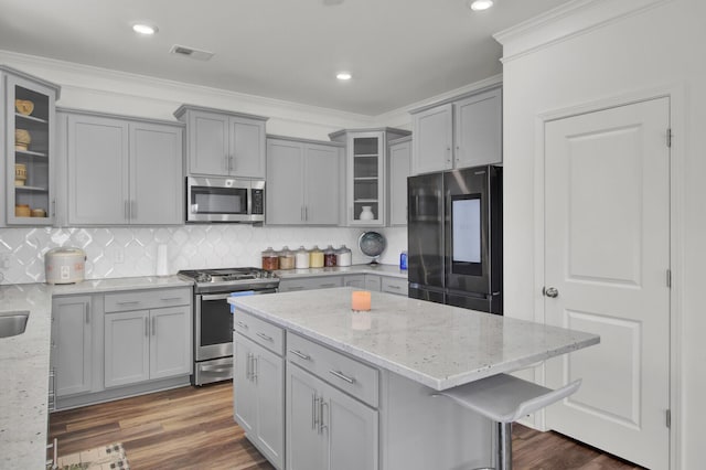 kitchen featuring ornamental molding, stainless steel appliances, backsplash, and light stone counters