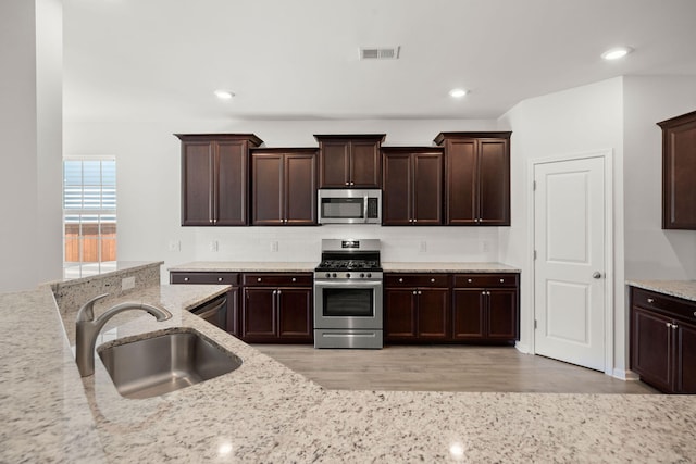 341 Witch Hazel St, Summerville, SC 29486 - kitchen featuring stainless steel appliances, a sink, dark brown cabinets, light stone counters, and light wood-style floors