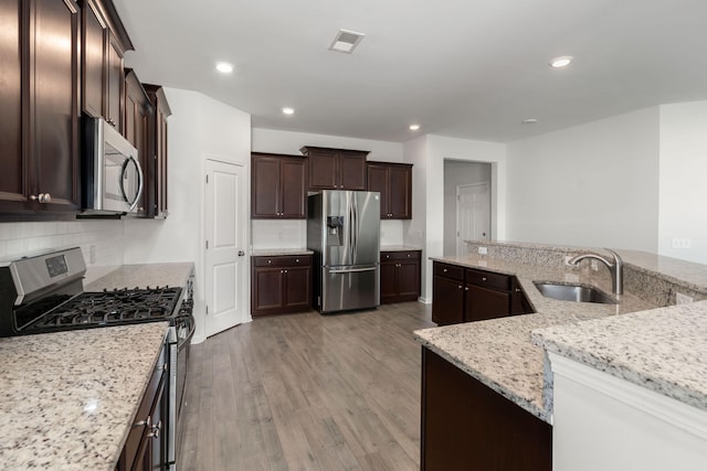 341 Witch Hazel St, Summerville, SC 29486 - kitchen with appliances with stainless steel finishes, a sink, light wood finished floors, dark brown cabinets, and backsplash