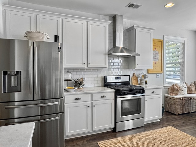 kitchen featuring stainless steel appliances, white cabinets, light countertops, and wall chimney range hood