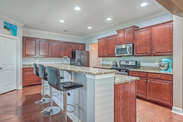 kitchen featuring fridge with ice dispenser, black gas range, a center island with sink, crown molding, and light hardwood / wood-style floors