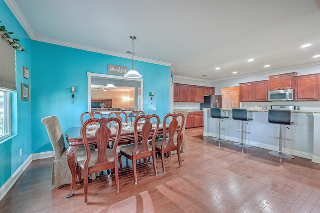 dining area featuring ornamental molding, wood-type flooring, and sink