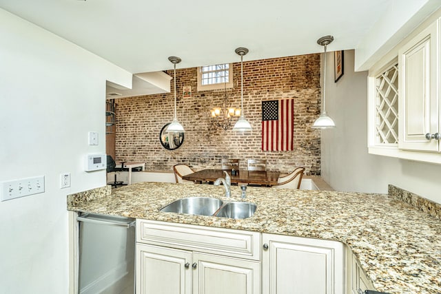 kitchen with light stone countertops, brick wall, hanging light fixtures, and sink