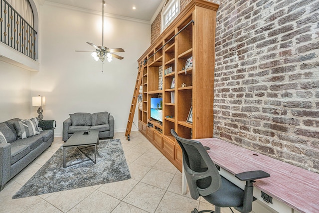 tiled office space with ceiling fan, crown molding, brick wall, and a high ceiling