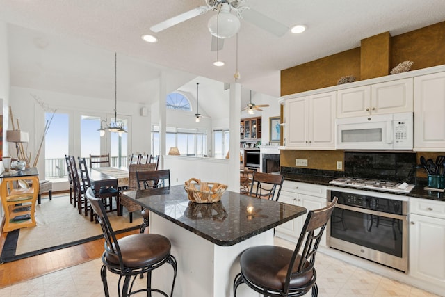 505 E Arctic Ave, Folly Beach, SC 29439 - kitchen with white appliances, a ceiling fan, a breakfast bar area, white cabinets, and vaulted ceiling